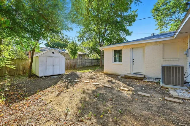 a backyard of a house with a large tree and wooden fence