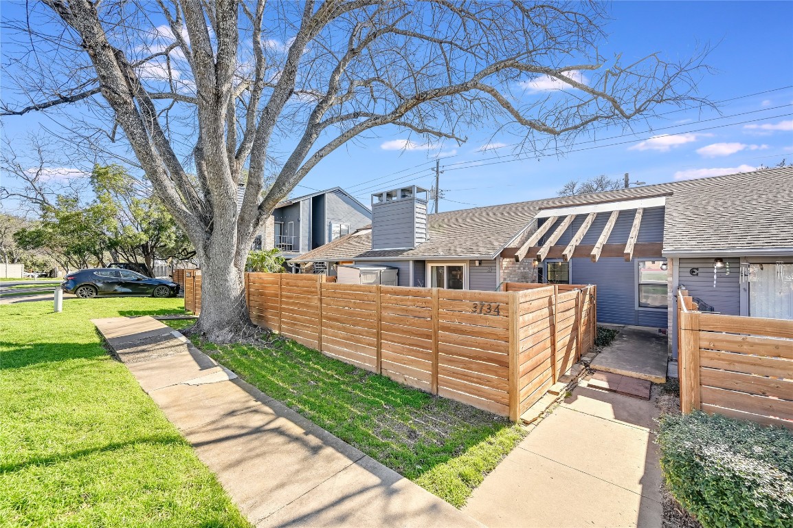 View of home's exterior featuring a fenced front yard, a chimney, a shingled roof, and a yard
