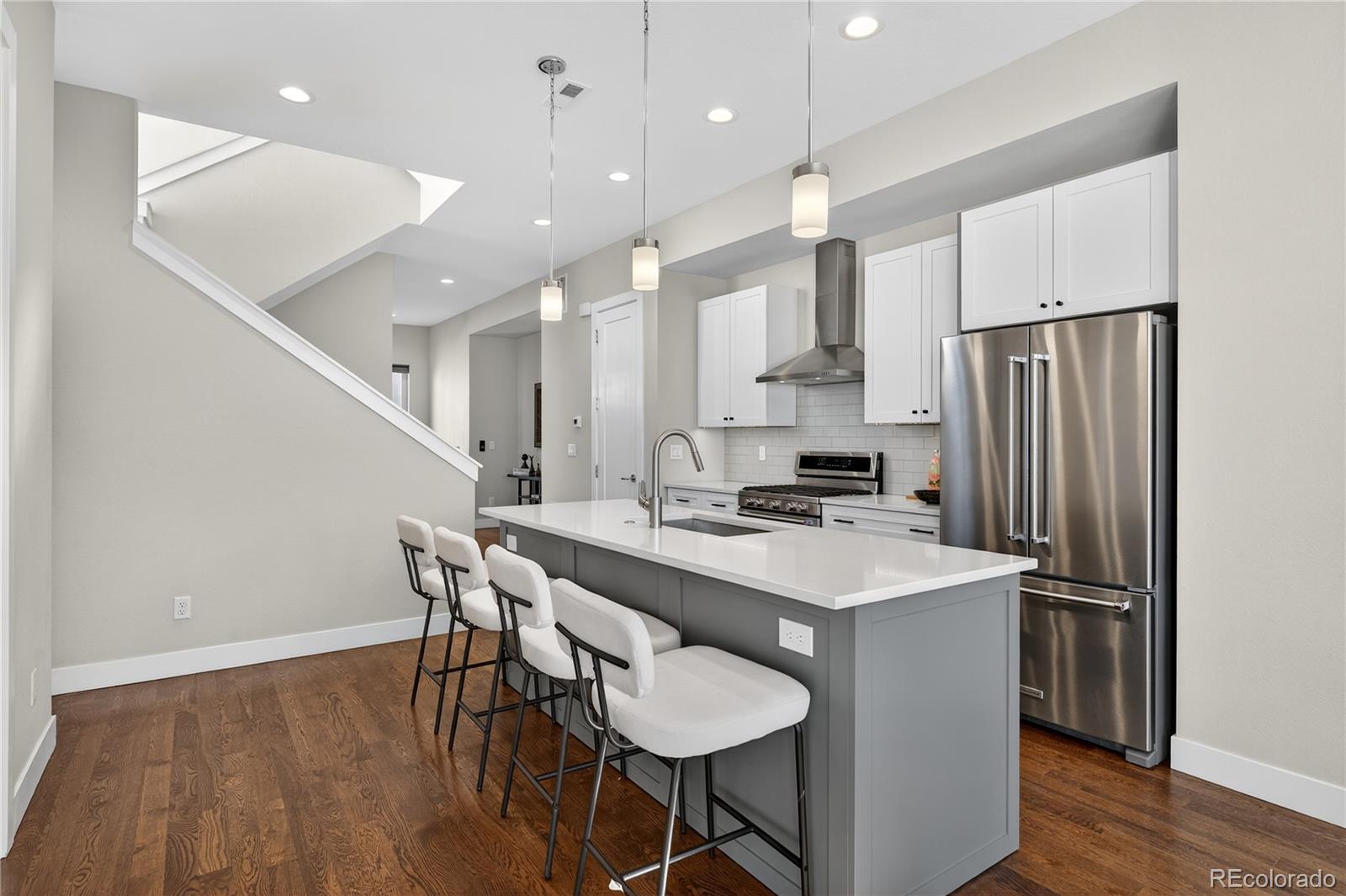 925 Inca Street, Unit 7 Denver, CO 80204 - Photo 15 of 42 a kitchen with stainless steel appliances a table chairs wooden floors and a view of living room