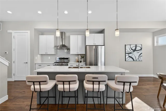 a kitchen with stainless steel appliances kitchen island granite countertop a dining table chairs and white cabinets