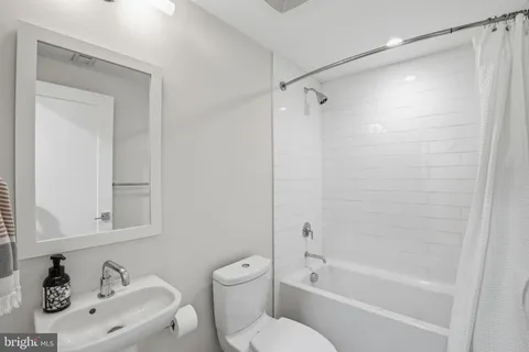 a bathroom with a bathtub shower sink vanity and toilet
