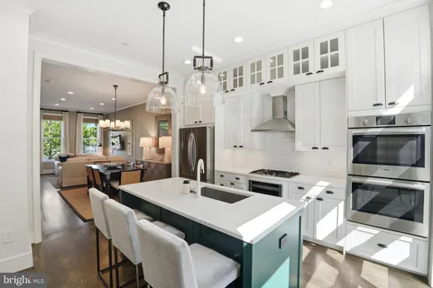 a kitchen with stainless steel appliances a stove a table a sink and a refrigerator