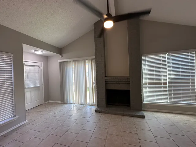 an empty room with windows and fan