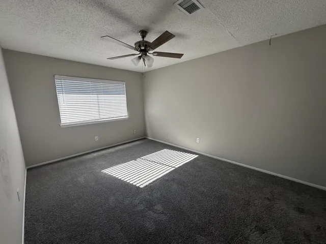 an empty room with a window and a ceiling fan