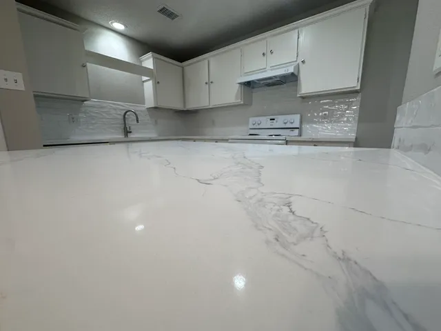 a kitchen with granite countertop white cabinets and a sink