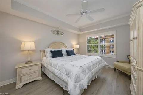 a large bed sitting in a bedroom next to a window with lamp on dresser and a chandelier