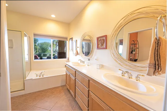 a spacious bathroom with a double vanity sink a mirror and a bathtub