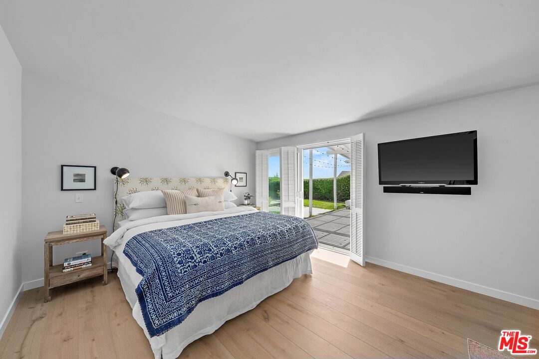 3516 Shoreheights Drive Malibu, CA 90265 - Photo 18 of 29 a bedroom with a large bed a flat tv screen and a book shelf