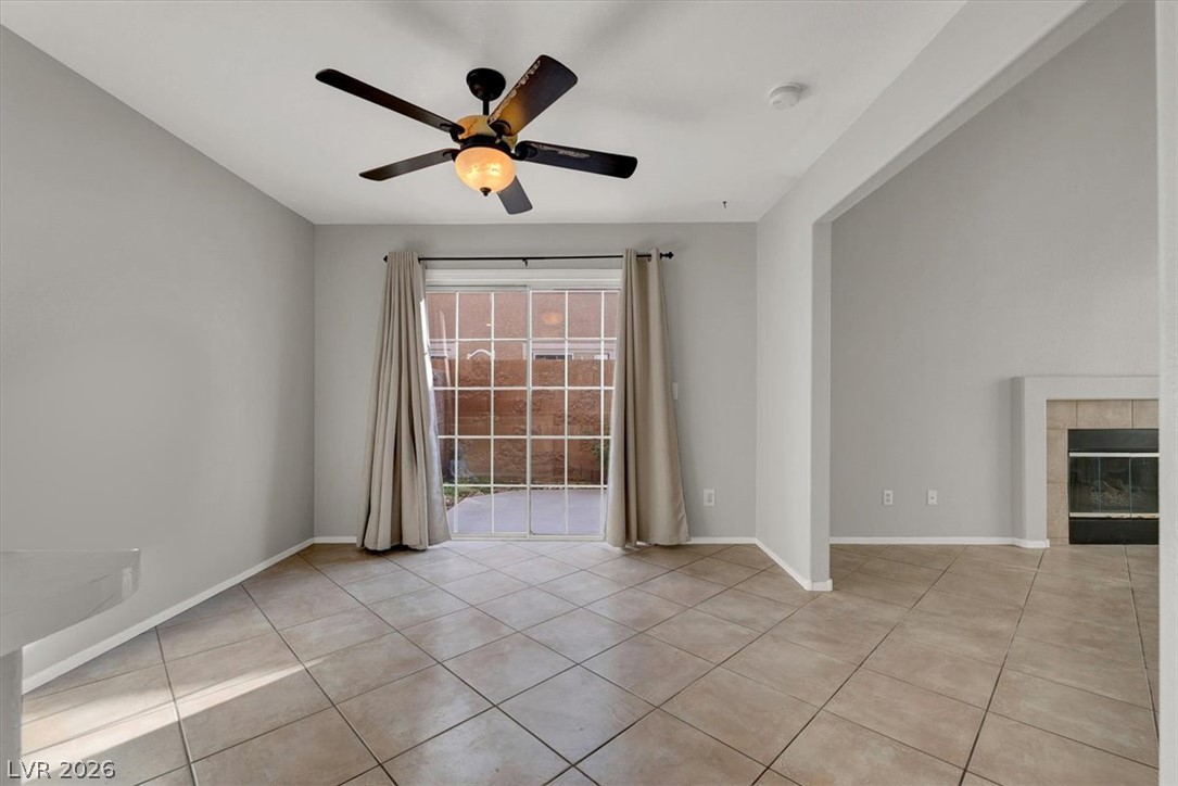 10148 Tree Bark Street Las Vegas, NV 89183 - Photo 17 of 37 Sliding glass doors open to a private outdoor space from this tiled living area, featuring a cozy fireplace.