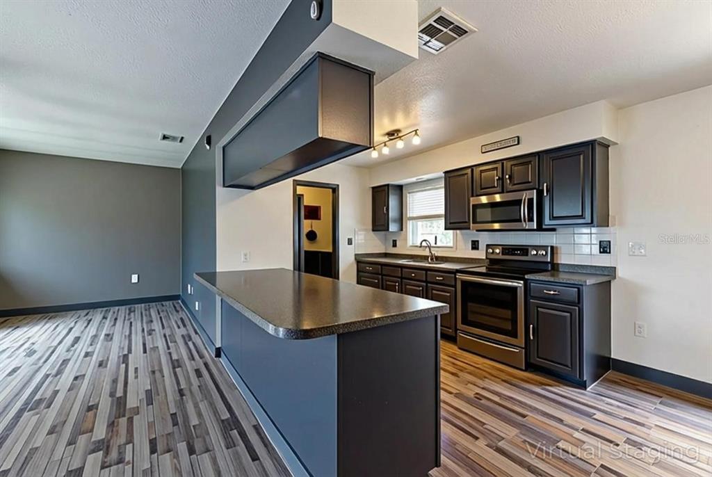 11327 Grove Street Leesburg, FL 34788 - Photo 12 of 40 a kitchen with stainless steel appliances granite countertop a stove a sink and a microwave