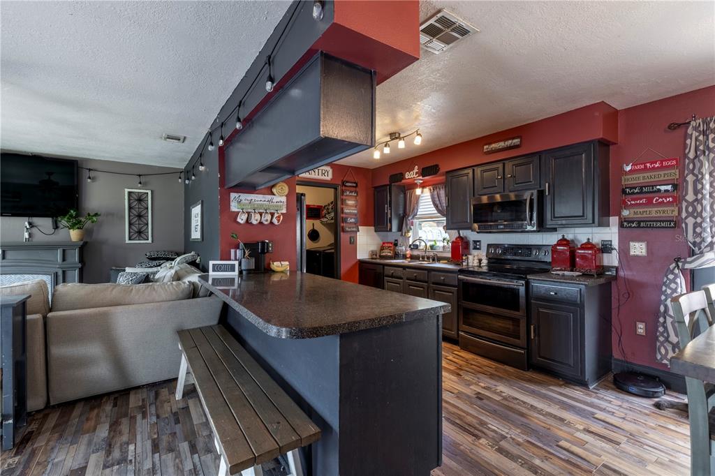 11327 Grove Street Leesburg, FL 34788 - Photo 14 of 40 a kitchen with stainless steel appliances granite countertop a sink dishwasher stove and refrigerator with wooden floor