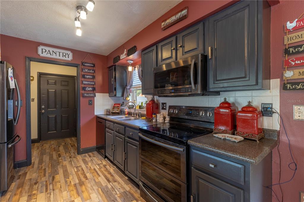 11327 Grove Street Leesburg, FL 34788 - Photo 15 of 40 a kitchen with stainless steel appliances granite countertop a stove sink and cabinets