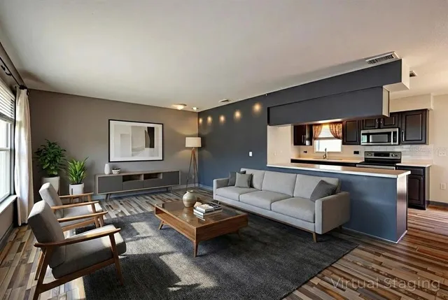 a kitchen with stainless steel appliances granite countertop a refrigerator a sink dishwasher a dining table and chairs with wooden floor