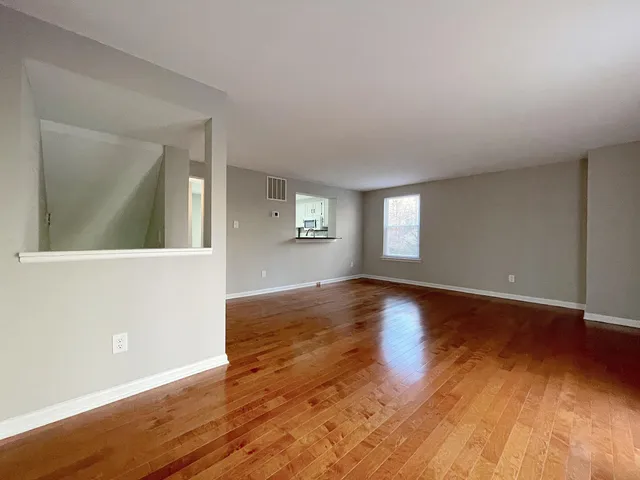 an empty room with wooden floor and windows