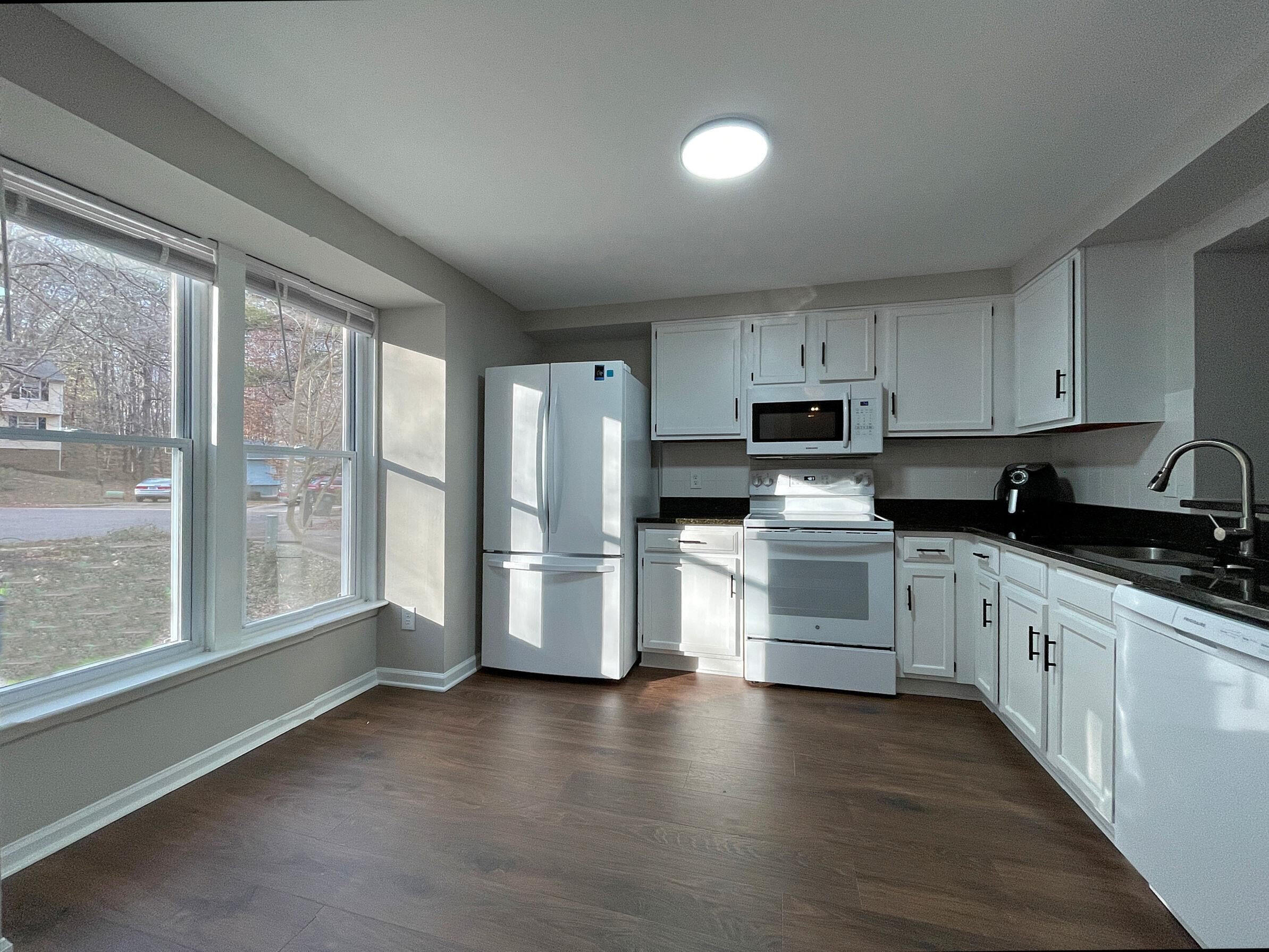 7328 Summerland Drive Raleigh, NC 27612 - Photo 7 of 27 a kitchen with granite countertop white cabinets and wooden floor