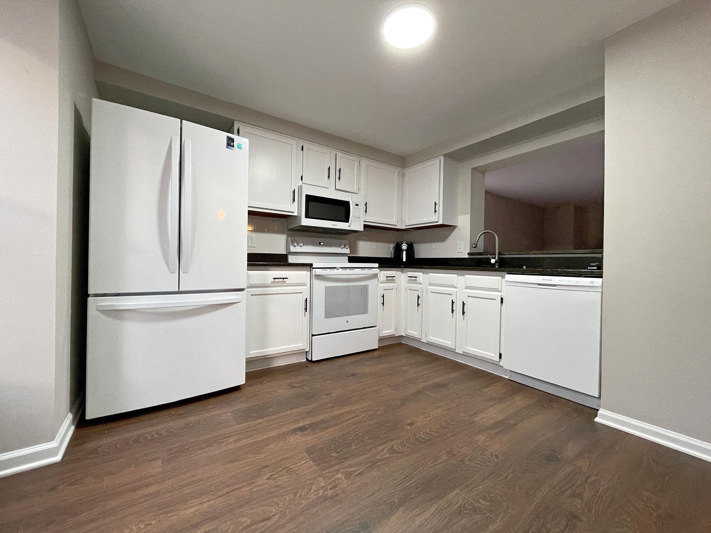 7328 Summerland Drive Raleigh, NC 27612 - Photo 9 of 27 a kitchen with white cabinets and white appliances