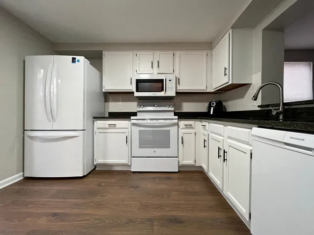 a kitchen with white cabinets and white appliances