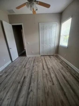a view of an empty room with wooden floor and a window