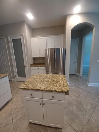 a view of kitchen with granite countertop cabinets and refrigerator