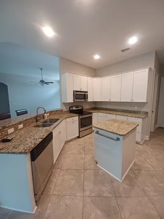 a kitchen with kitchen island granite countertop a stove sink and cabinets