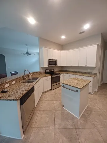 a kitchen with kitchen island granite countertop a stove sink and cabinets