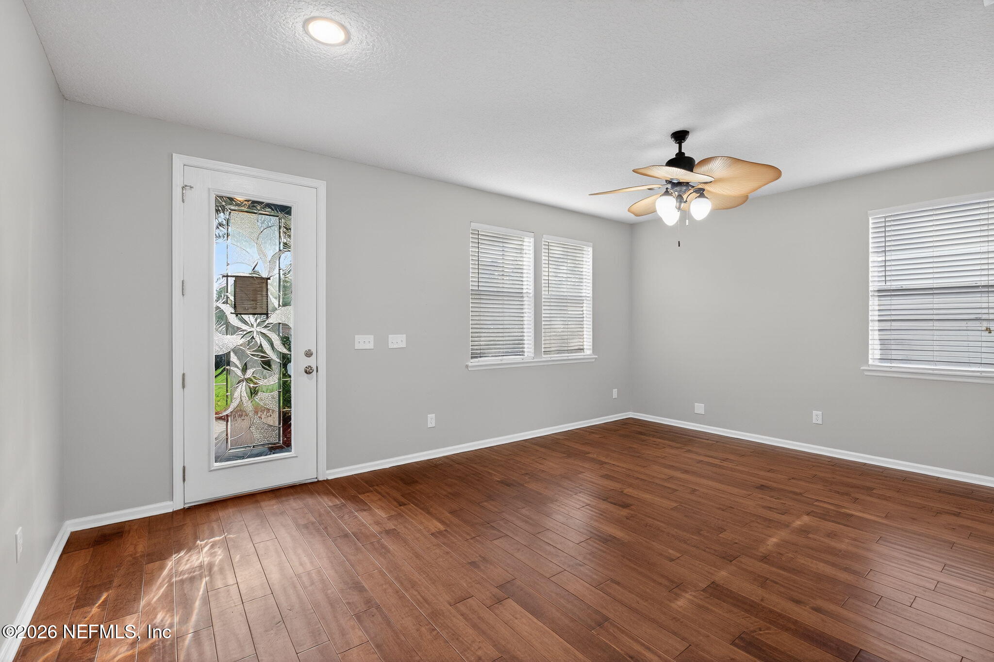 76134 Tideview Lane Yulee, FL 32097 - Photo 18 of 44 an empty room with wooden floor chandelier fan and windows