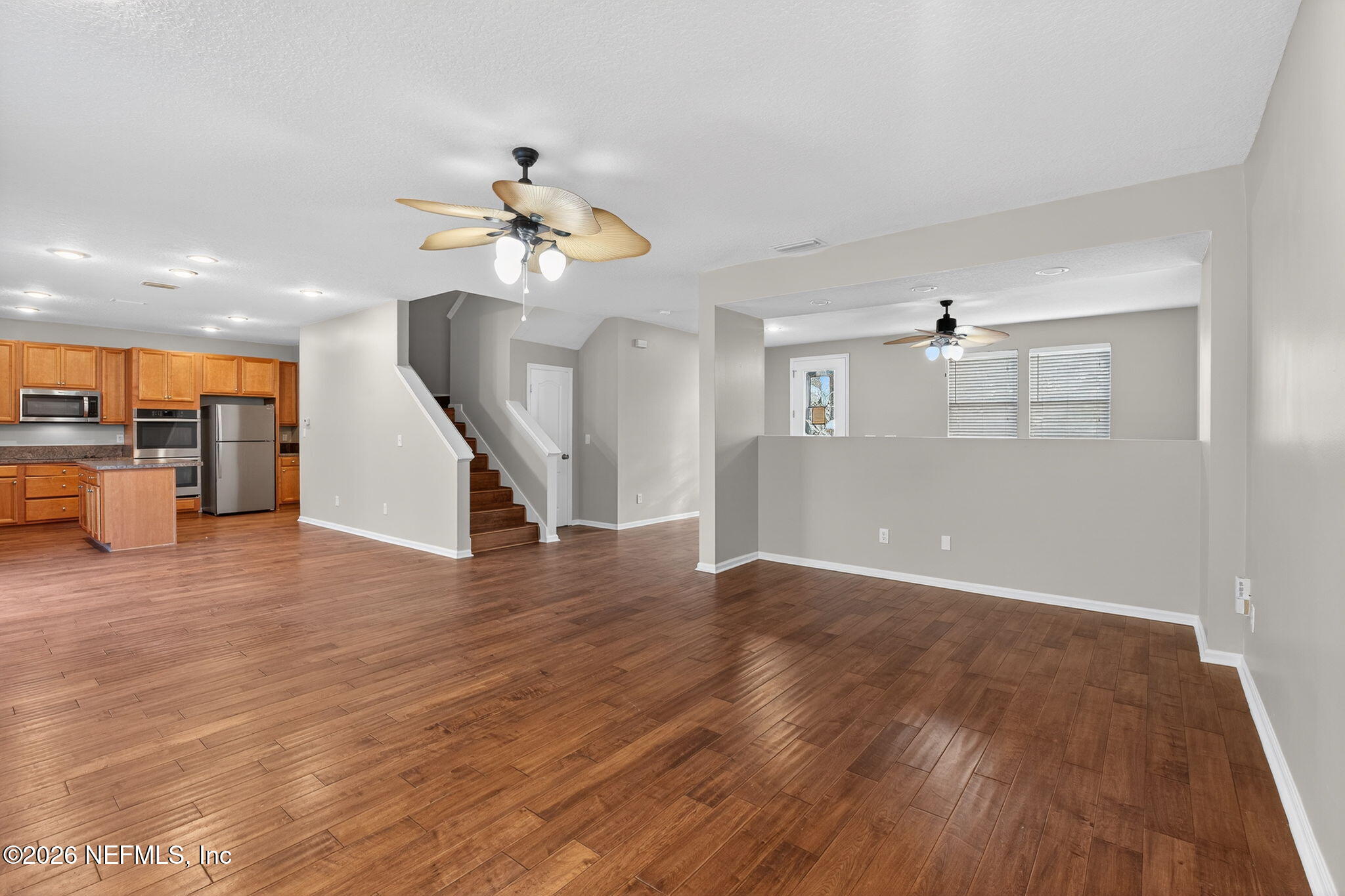 76134 Tideview Lane Yulee, FL 32097 - Photo 23 of 44 a view of a kitchen and an empty room with wooden floor and a ceiling fan