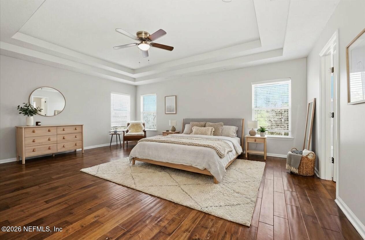 76134 Tideview Lane Yulee, FL 32097 - Photo 10 of 44 a spacious bedroom with a bed a chandelier and a dresser