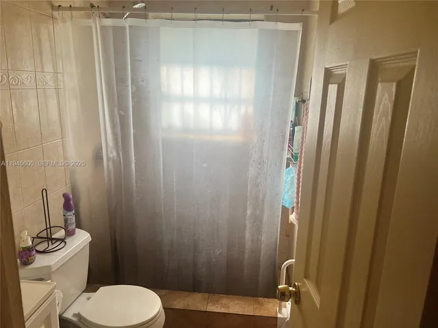 a bathroom with a sink a toilet a mirror and shower curtain