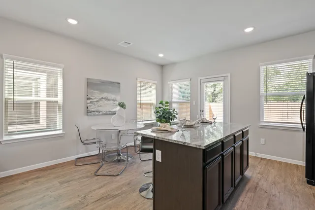 a kitchen with granite countertop a stove a sink a dining table and chairs