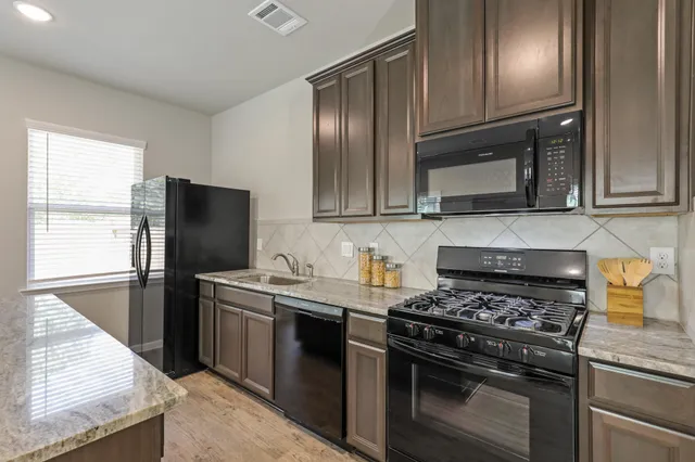 a kitchen with stainless steel appliances granite countertop a stove microwave and sink