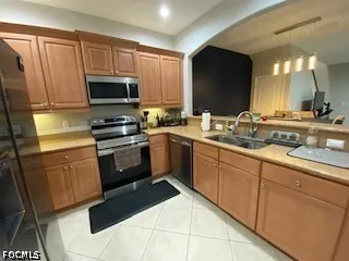 a room with stainless steel appliances a refrigerator a sink a stove a microwave a counter top and cabinets