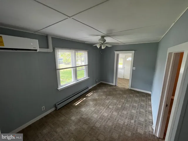 an empty room with chandelier fan and windows