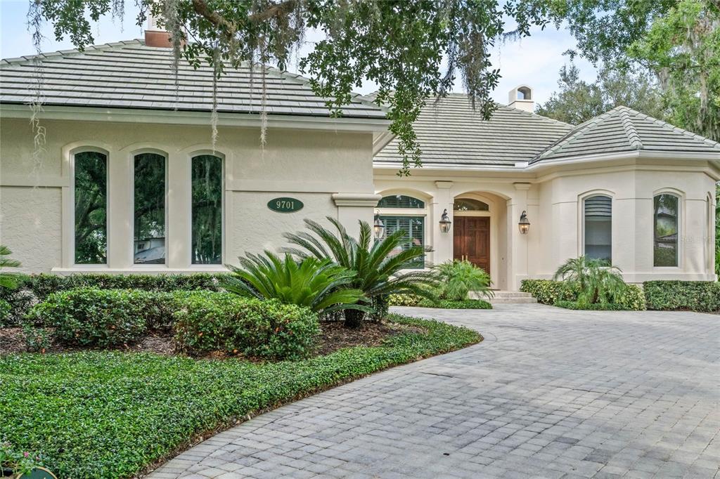 9701 Lake Isleworth Court Windermere, FL 34786 - Photo 2 of 31 a view of a white house with potted plants and a table and chairs