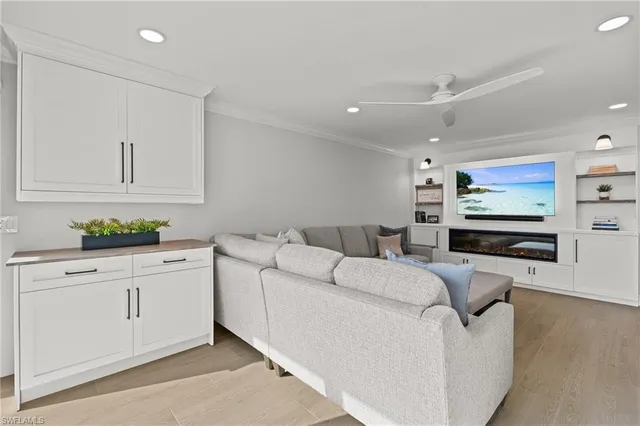 a living room with furniture a flat screen tv and kitchen view
