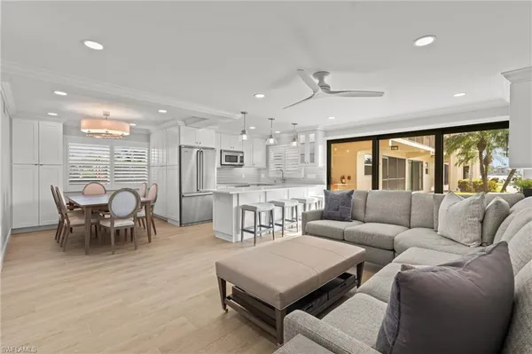 a living room with furniture kitchen view and a large window
