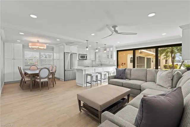 a living room with furniture kitchen view and a large window