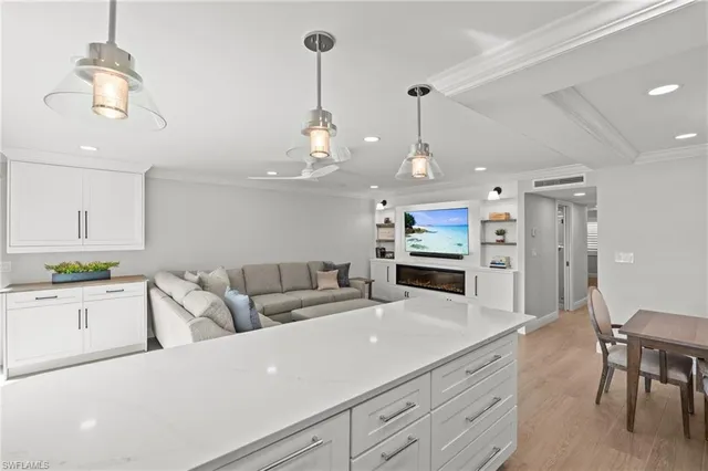 a living room with furniture kitchen view and a chandelier