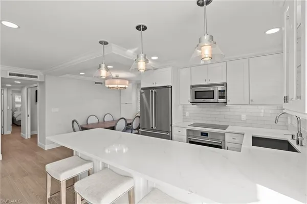 a kitchen with stainless steel appliances a table a sink and microwave