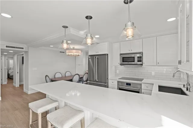a kitchen with stainless steel appliances a table a sink and microwave