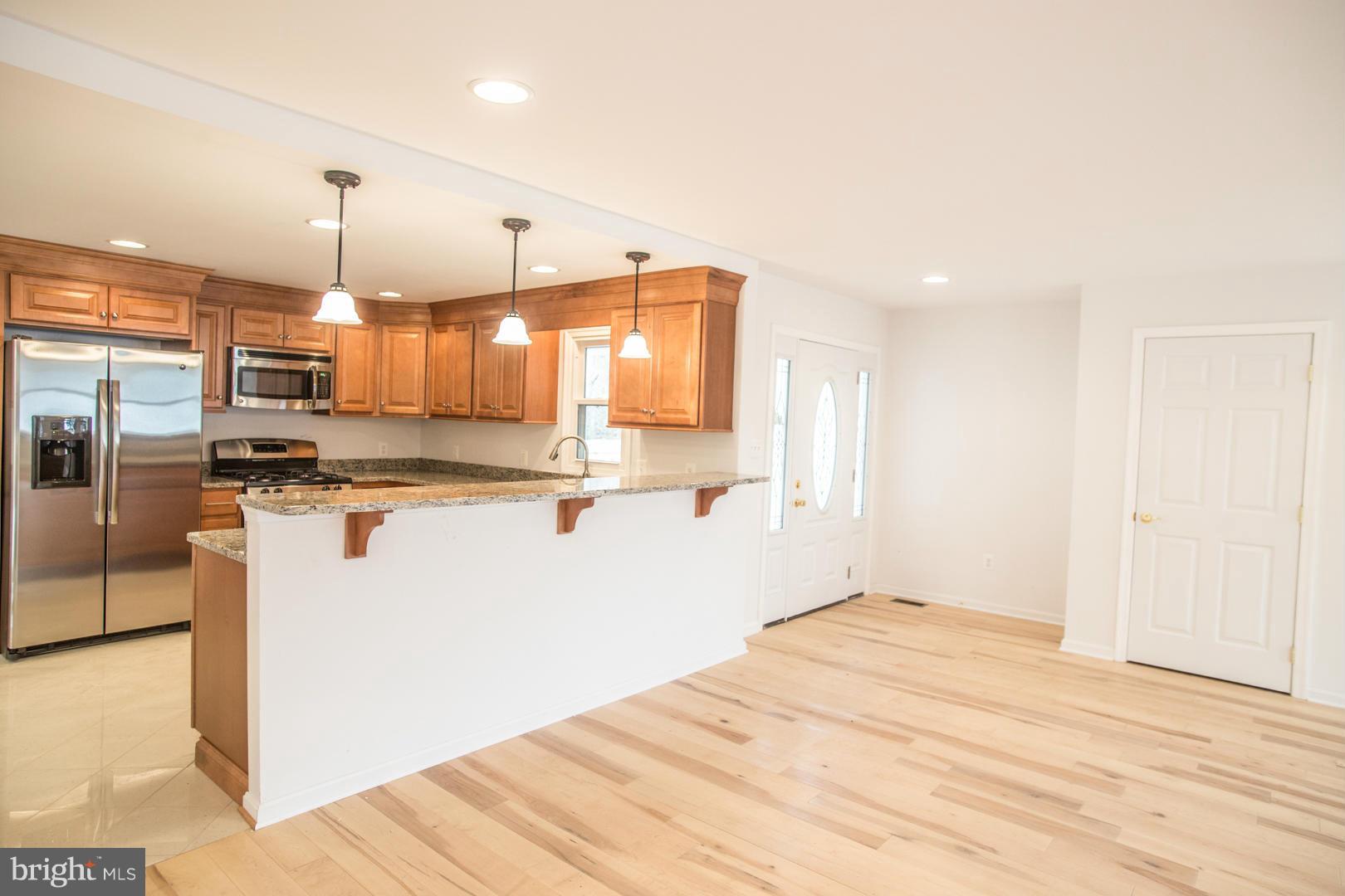 1995 Sixes Road Prince Frederick, MD 20678 - Photo 4 of 30 a kitchen with stainless steel appliances kitchen island granite countertop a refrigerator a sink a stove and oven with wooden floor