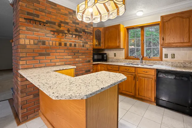a kitchen with granite countertop a sink a counter top space and cabinets