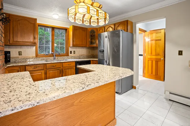a large kitchen with kitchen island granite countertop wooden cabinets a granite counter tops and a large window