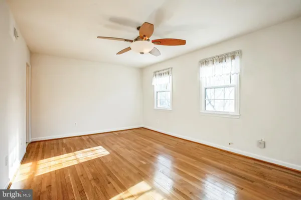 a view of an empty room with window and wooden floor