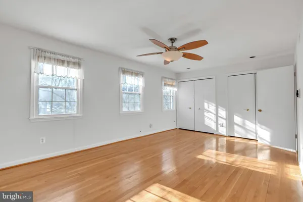 a view of empty room with wooden floor and fan