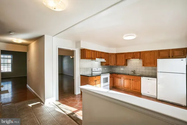 a kitchen with stainless steel appliances granite countertop a refrigerator a stove and a sink with wooden cabinets