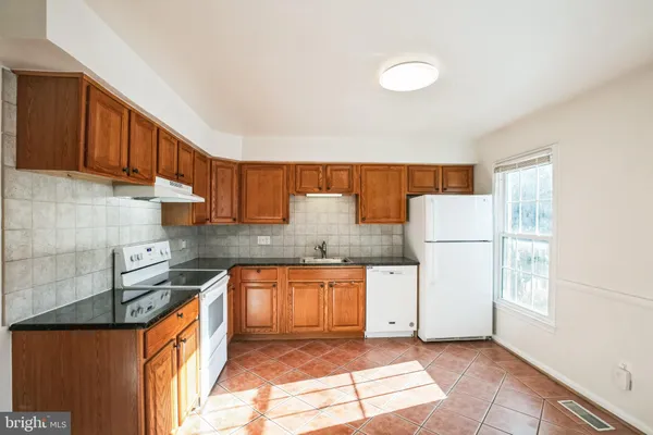 a kitchen with granite countertop a sink a stove and a refrigerator
