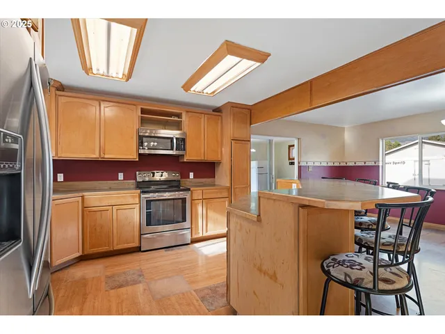 a kitchen view with a sink dishwasher a dining table and chairs with wooden floor