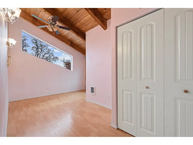 a view of an empty room with a window and wooden floor