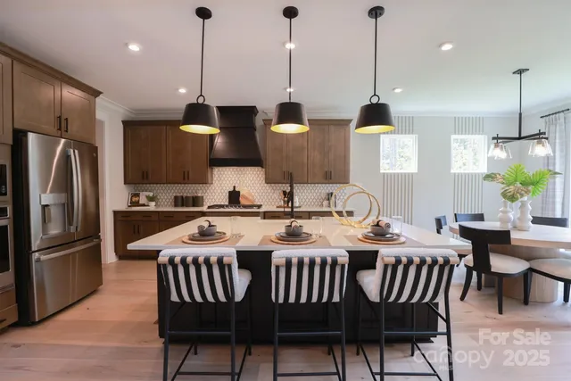 a kitchen with stainless steel appliances granite countertop a sink a stove a refrigerator with a dining table and chairs